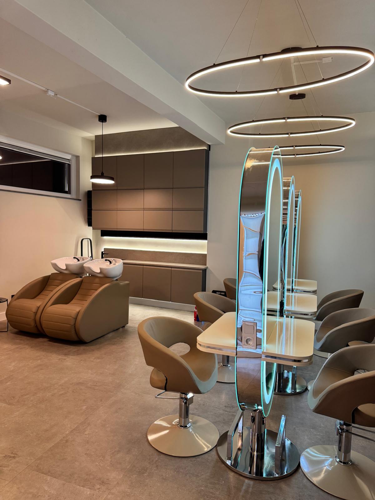 Wasstoel, ringlampen en verlichte boogspiegels bij het grote raam van de salon