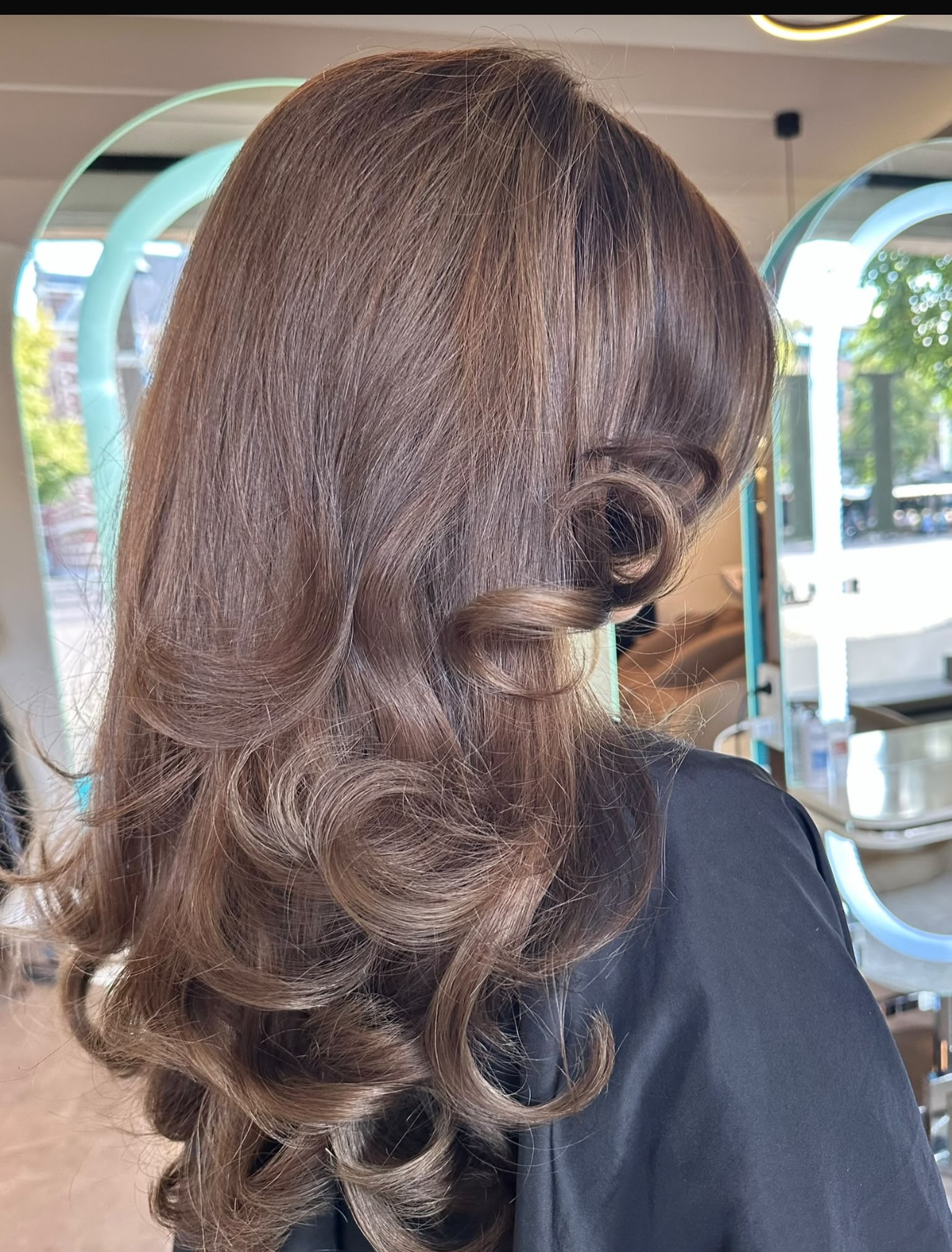 Glanzende blowout met grote krullen in lang bruin haar