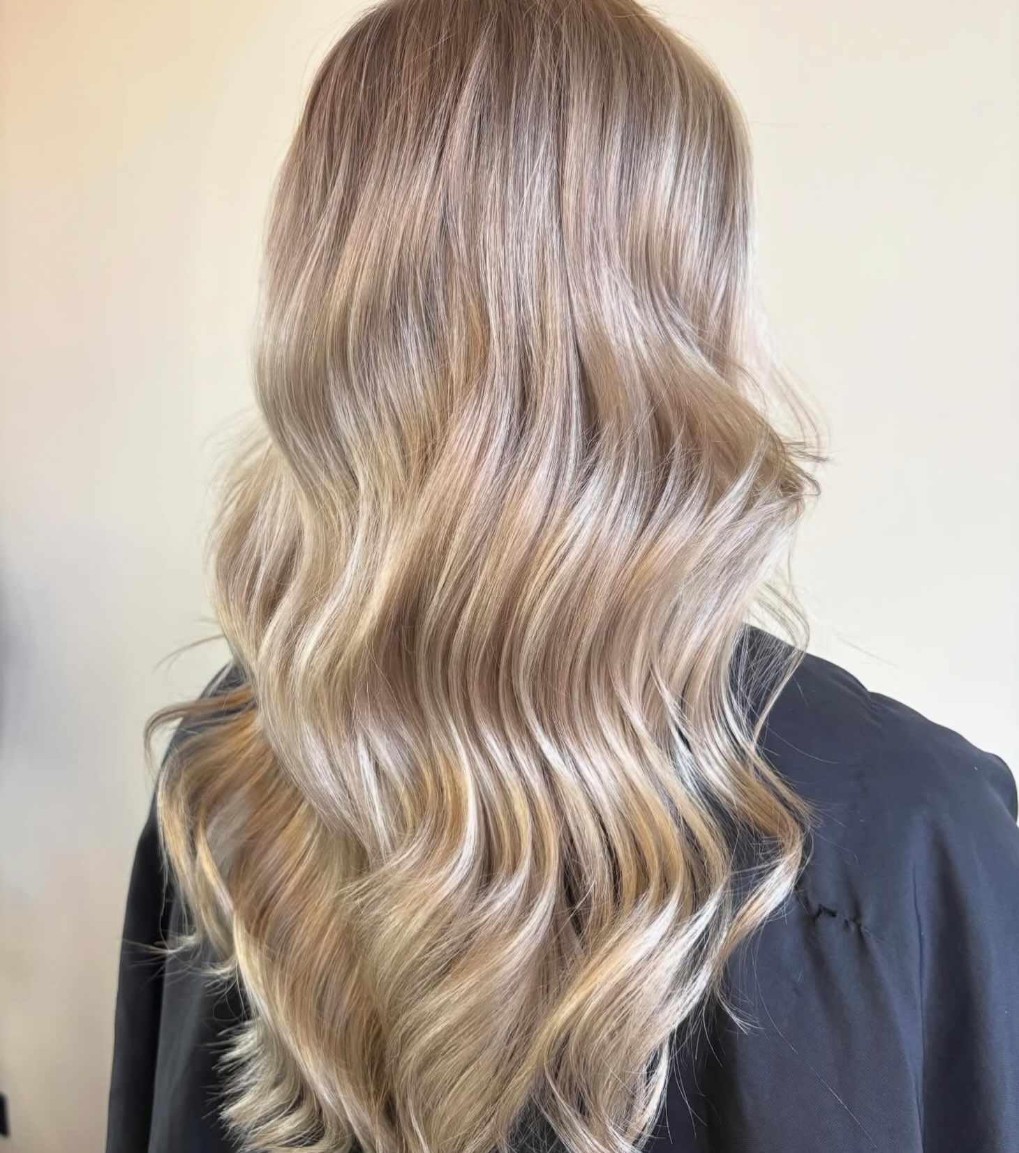 Lang blond haar met balayage en losse golven, van achteren gezien